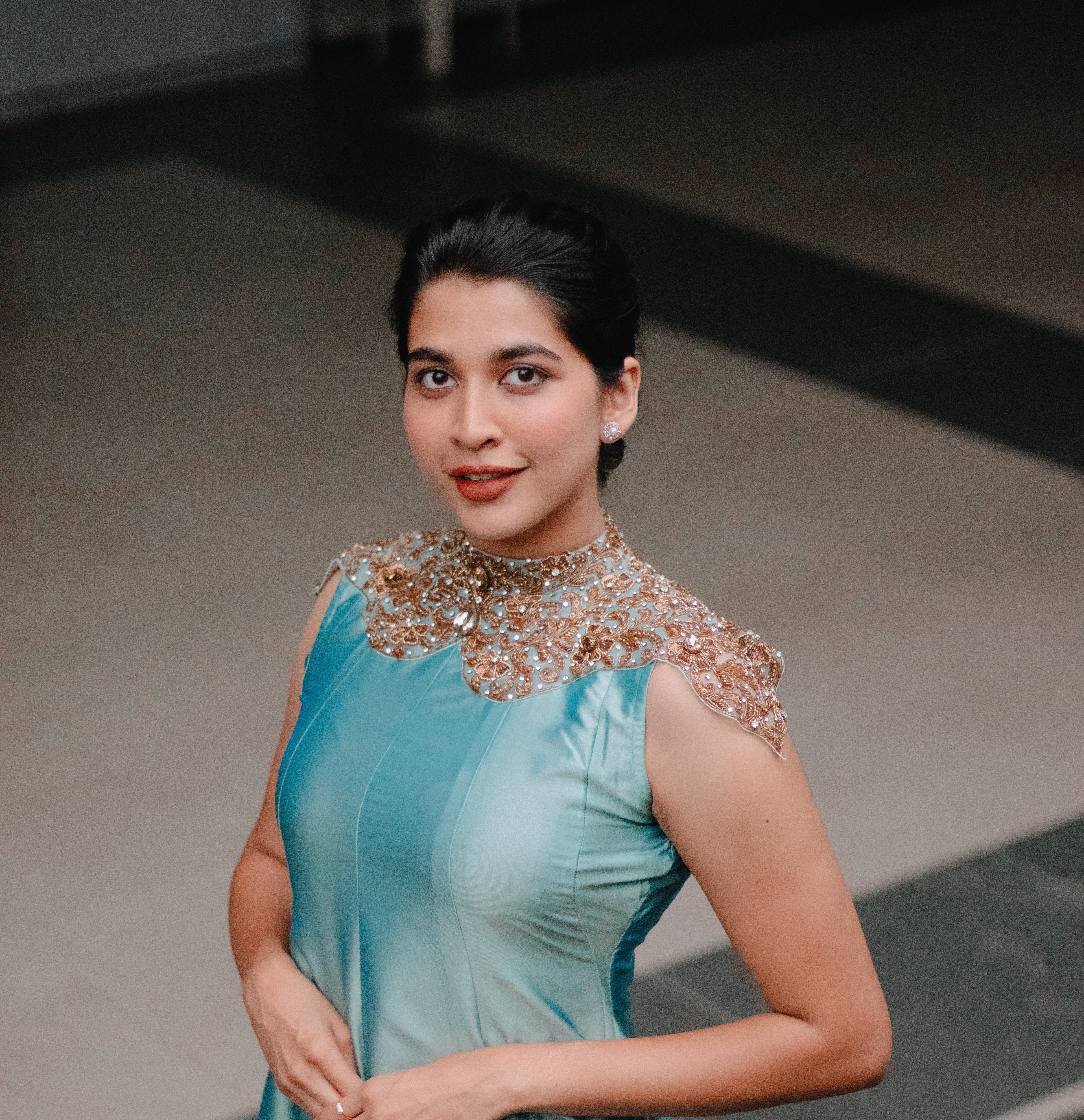 Woman in a teal blue dress with intricate detailing